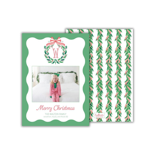 A Christmas card featuring a young girl in a red and white outfit, with a wreath and ribbon design, and a photo of her on the front.