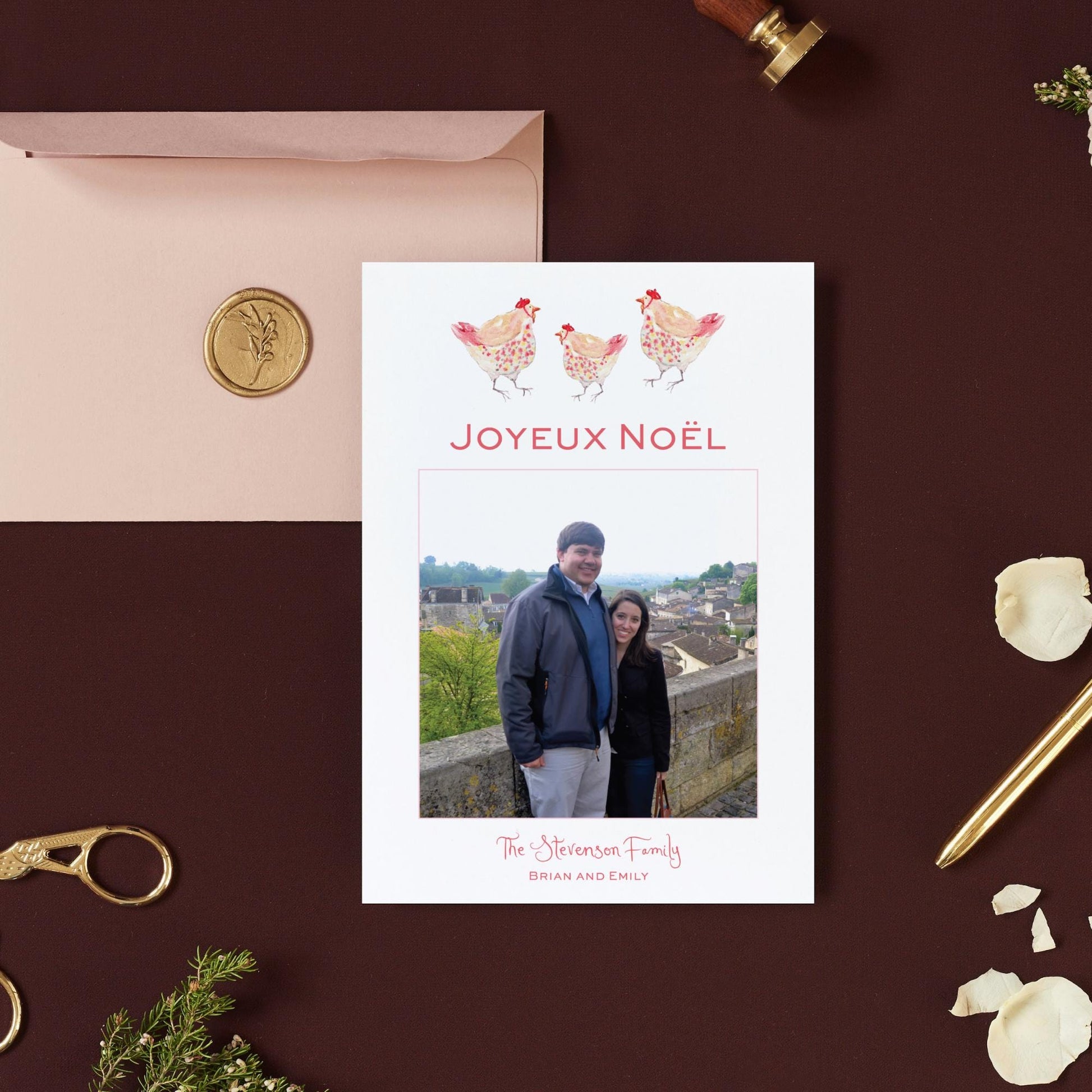 a Christmas card with a photo of a man and a woman standing together, along with a stamp and a pen.