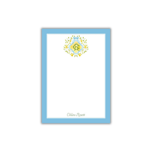 A blue-bordered, white-blank card with a decorative floral design on the top.