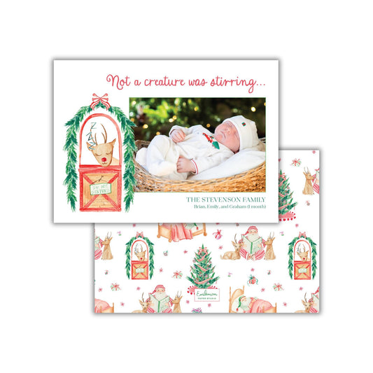 A Christmas card featuring a baby in a white outfit, surrounded by festive holiday decorations such as reindeer, snowmen, and Christmas trees.