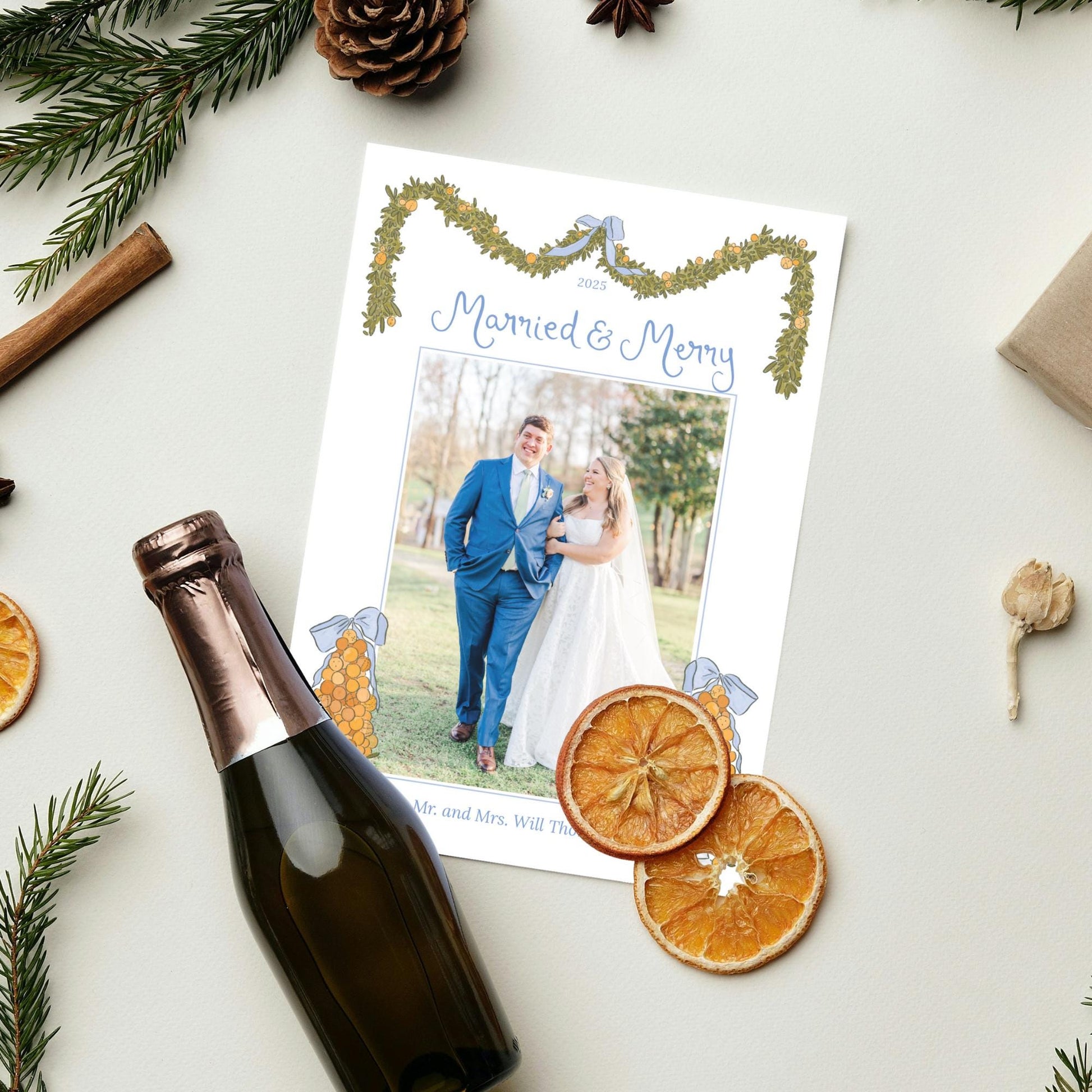 A wedding invitation card with a photo of a couple, surrounded by holiday decorations such as pine branches, pinecones, and dried orange slices.