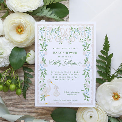 The image is a baby shower invitation featuring a floral design with white flowers and green leaves.