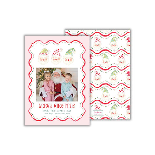 A rectangular 5 x 7 inch holiday greeting card with a pink background, with a wavy red polka dot border and three hand-painted watercolor Santas. "Merry Christmas" is written below the photo in a playful, quirky font, and the family's names are below that. The back o the card features squiggly red polka dotted stripes, with Santa faces interspersed among it.