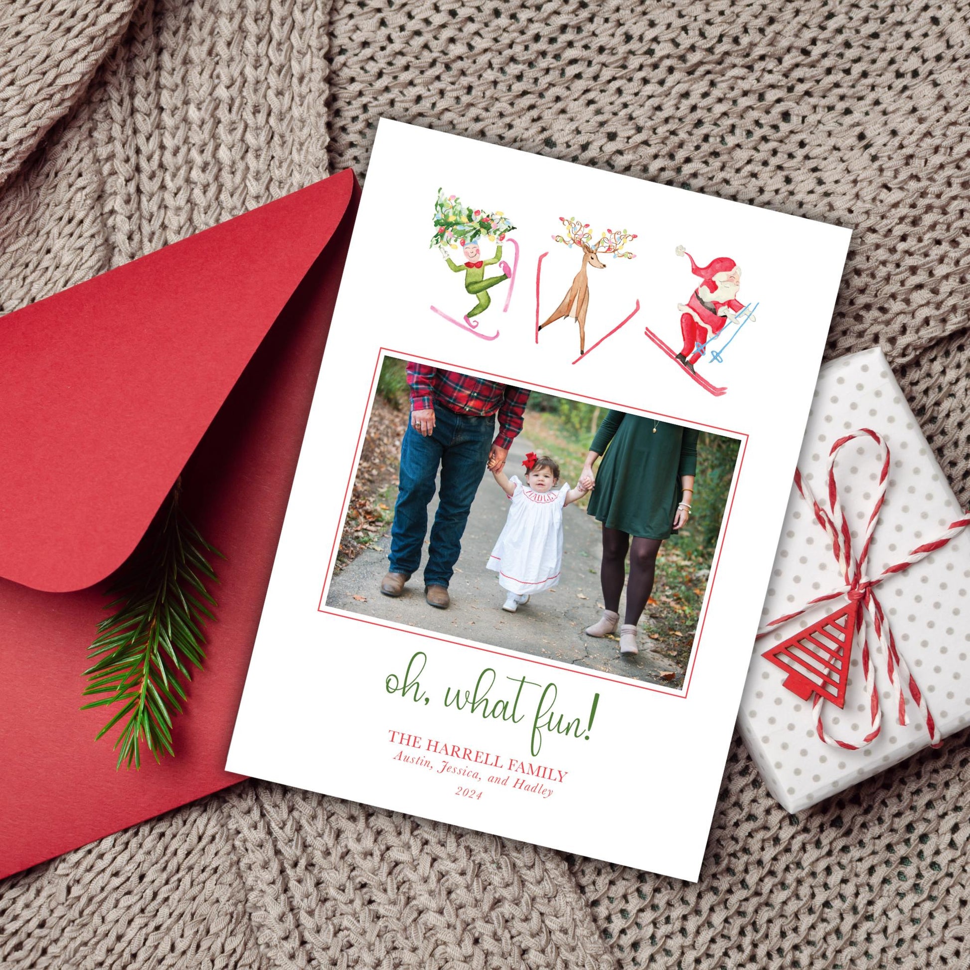 A holiday-themed card with a photo of a family, along with a red envelope, a gift box, and a pine branch.