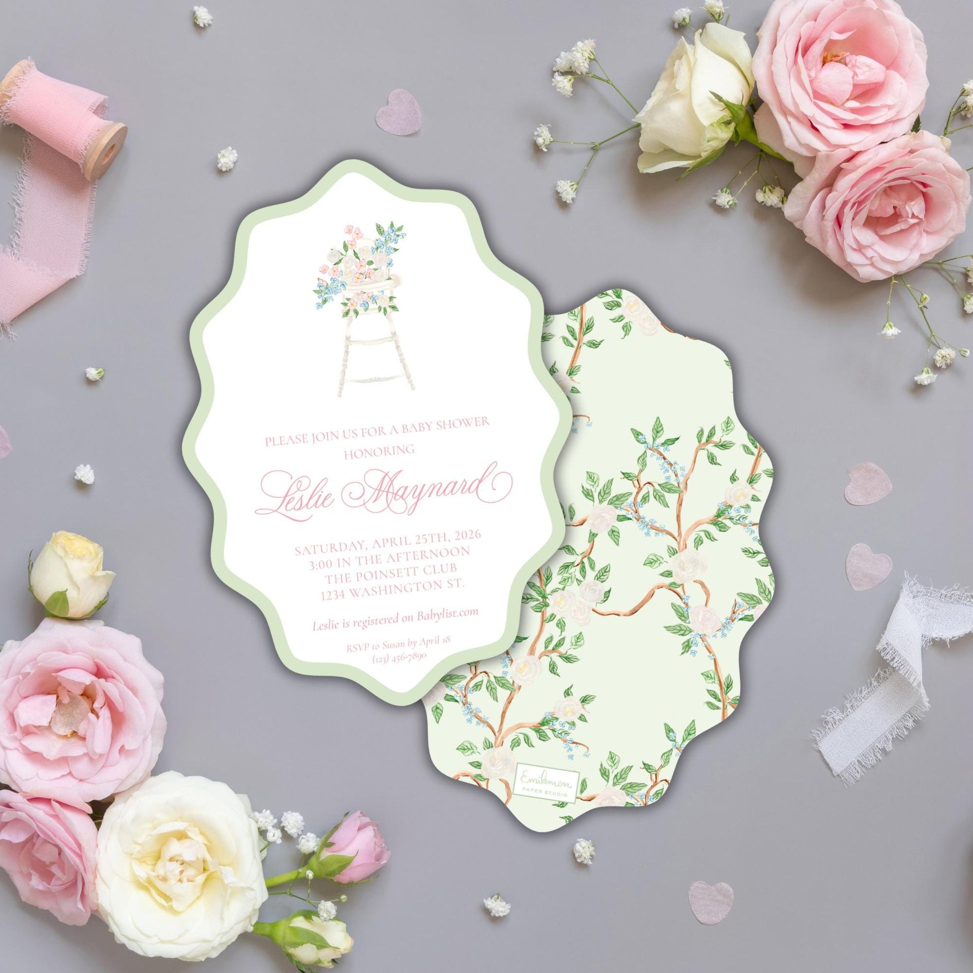 a baby shower invitation with a floral design, surrounded by pink roses and white flowers on a gray background.