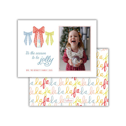 A holiday greeting card featuring a young girl in a red dress holding a snow globe, with a festive background and a repeating pattern of the word "lala" on the card's background.
