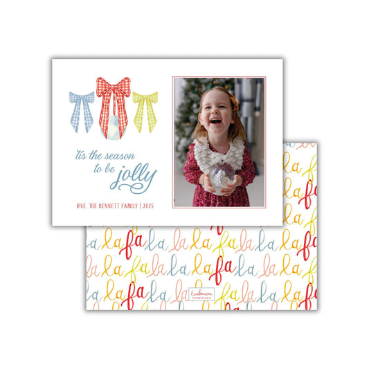 A holiday greeting card featuring a young girl in a red dress holding a snow globe, with a festive background and a repeating pattern of the word &quot;lala&quot; on the card&#39;s background.