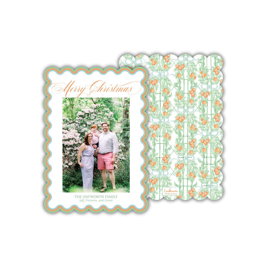 A family portrait of a man, woman, and child in a garden setting, with a scalloped edge frame and a repeating pattern of orange flowers on a green background.