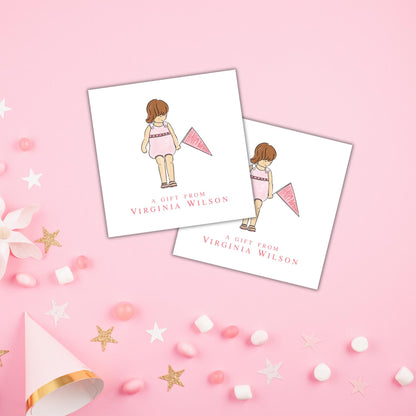 two white cards with illustrations of a girl and a pink flag, along with the text "A gift from VIRGINIA WILSON". The cards are placed on a pink background with scattered confetti and stars.