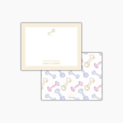 two pieces of paper with a repeating pattern of baby bottles and rattle toys. The text on the paper reads "FROM THE NURSES OF BABY COOPER".