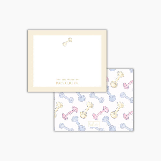 two pieces of paper with a repeating pattern of baby bottles and rattle toys. The text on the paper reads "FROM THE NURSES OF BABY COOPER".