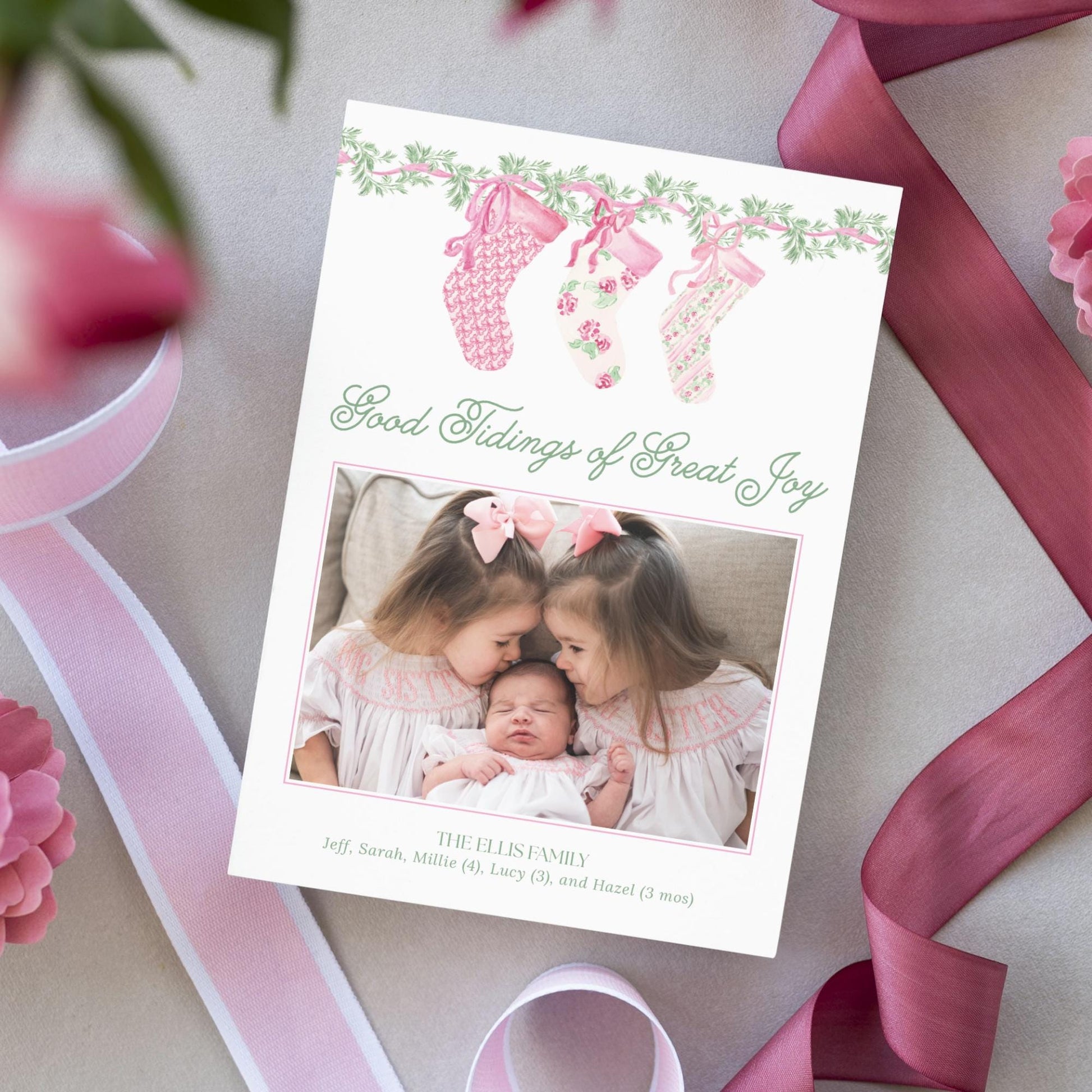 A handmade greeting card with a photo of two young girls, presumably sisters, sitting together and smiling. The card has a pink and white color scheme and features a ribbon design.