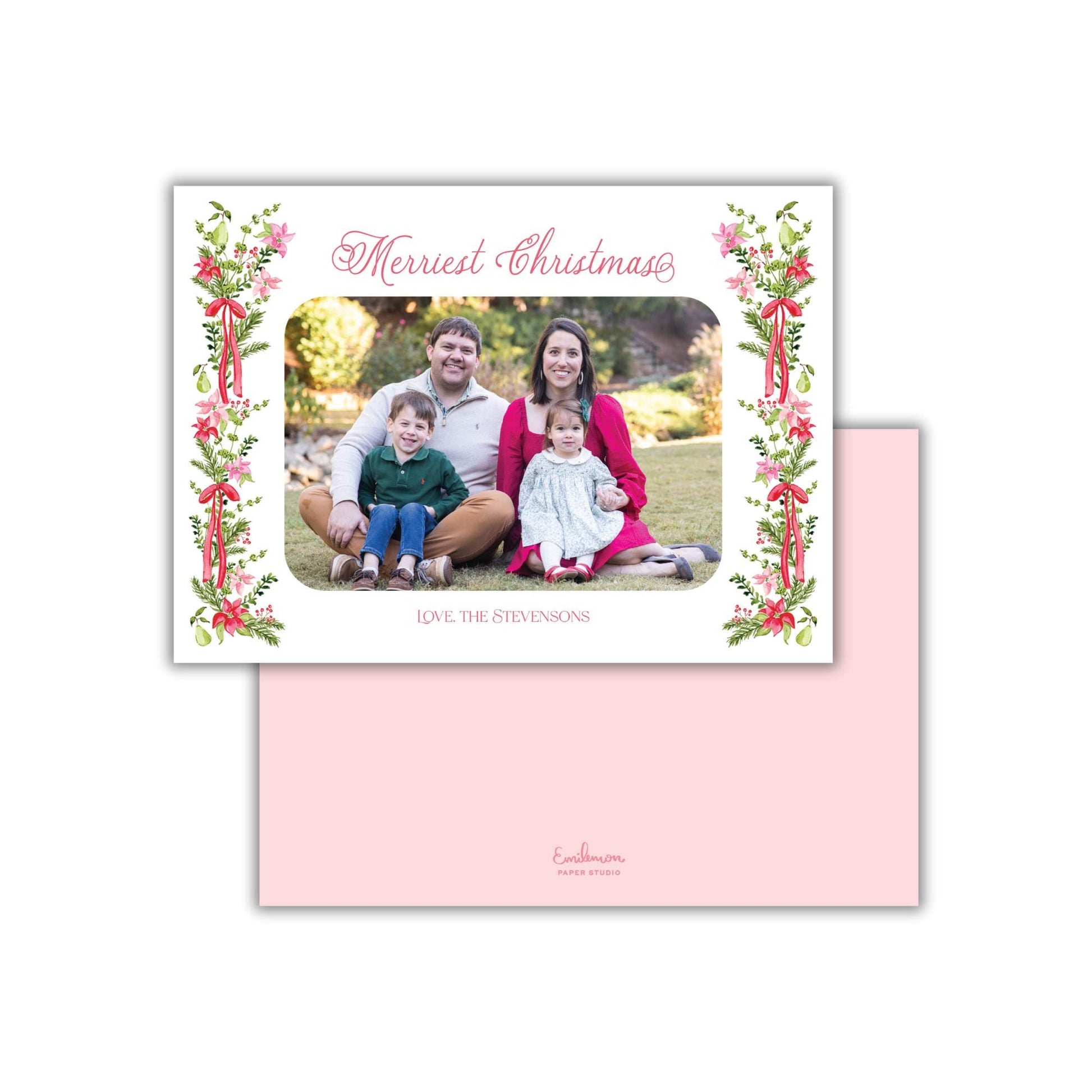 A family portrait of a man, woman, and two children sitting together on a grassy area, with a floral border around the photo.