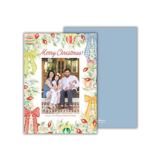 A family portrait of a man, woman, and two children sitting on a porch, surrounded by Christmas decorations.