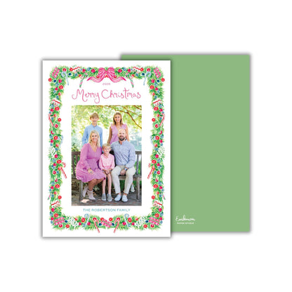 A family portrait of a group of people, likely a family, with a festive wreath border surrounding the image.