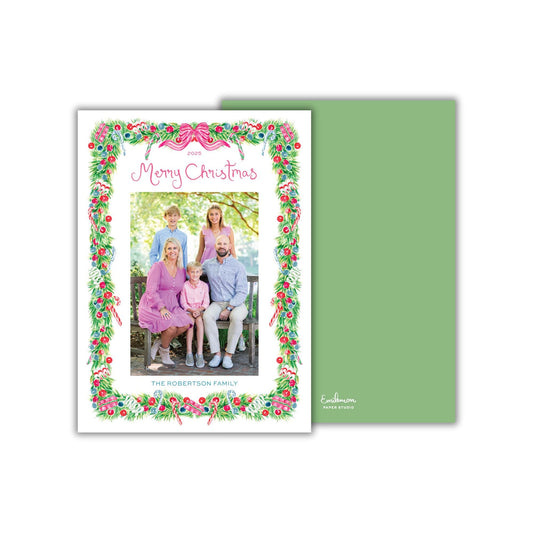 A family portrait of a group of people, likely a family, with a festive wreath border surrounding the image.