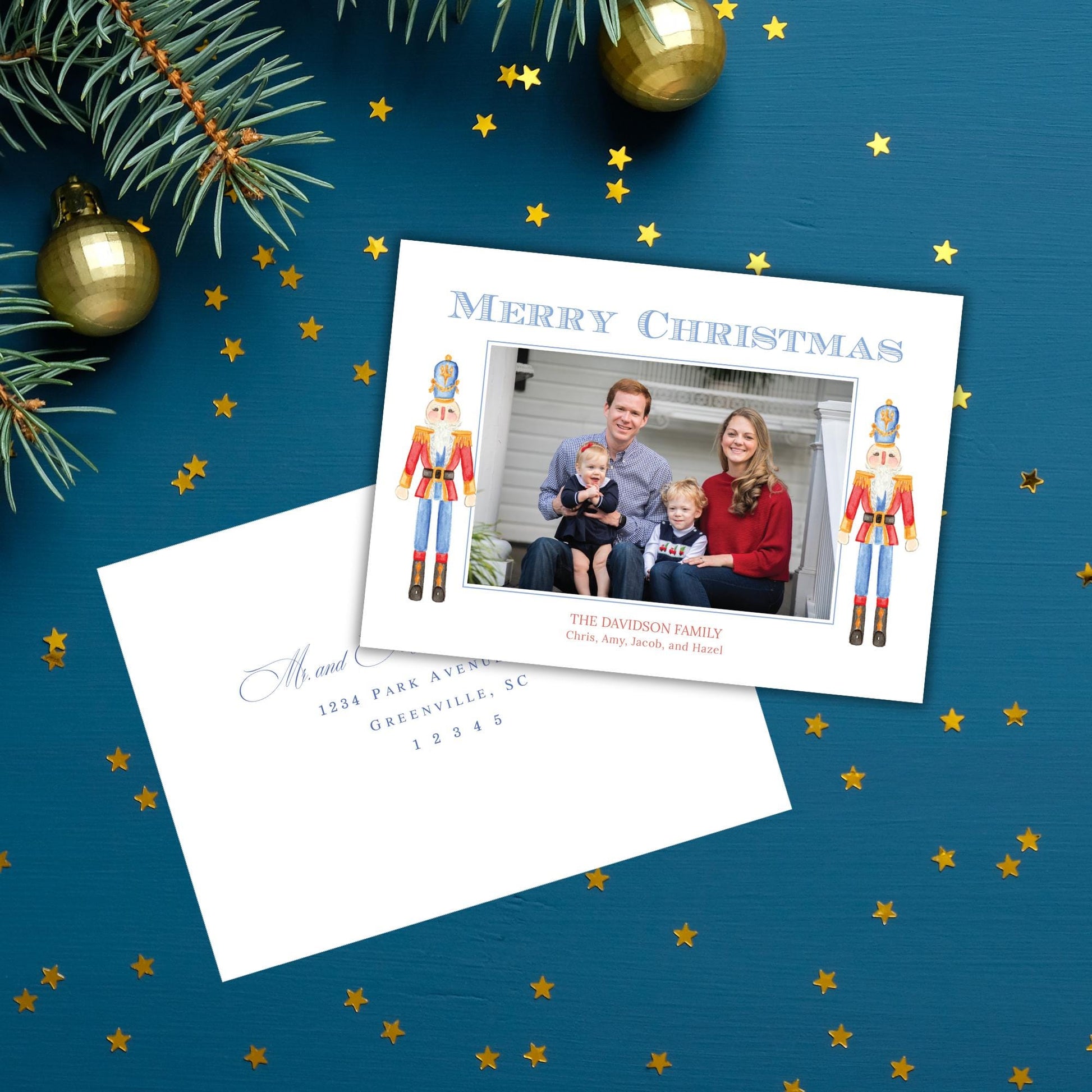 A Christmas card with a family photo and a note, placed on a blue background with gold stars scattered around it.