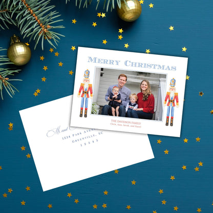 A Christmas card with a family photo and a note, placed on a blue background with gold stars scattered around it.