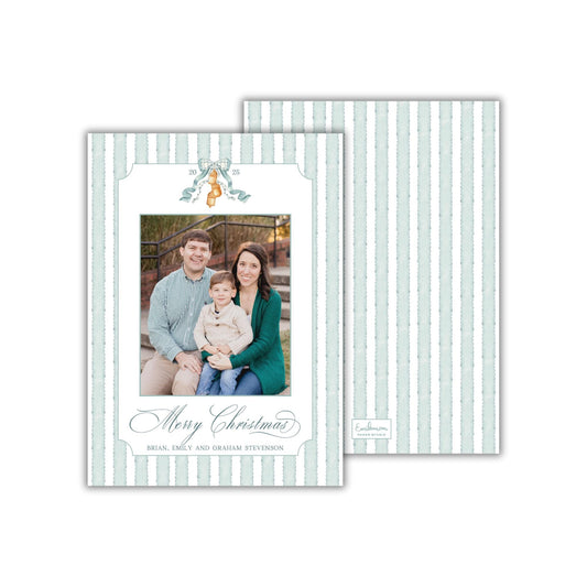 A family portrait of a man, woman, and child sitting together on a bench, with a &quot;Merry Christmas&quot; greeting in the center.