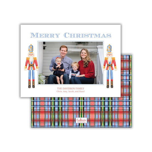 A family portrait of a man, woman, and child, with nutcracker figures on either side of the photo. The text &quot;Merry Christmas&quot; is displayed above the photo, and &quot;THE DAVIDSON FAMILY Chris, Amy, Jacob, and Hazel&quot; is written below the image.