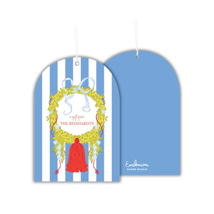 a blue and white striped tag with a decorative wreath and a red tassel.