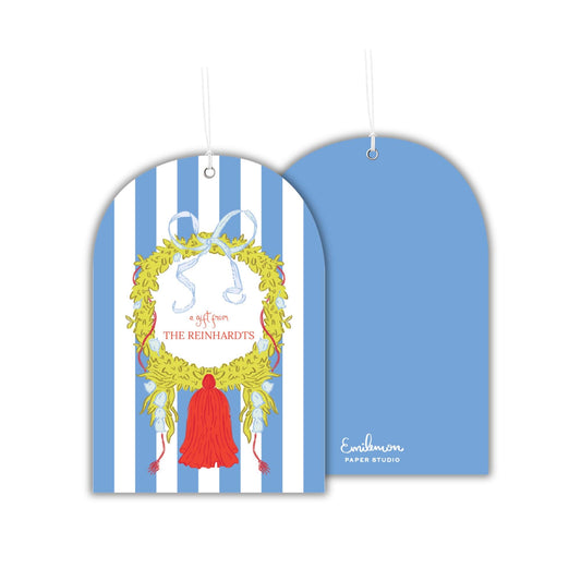 a blue and white striped tag with a decorative wreath and a red tassel.