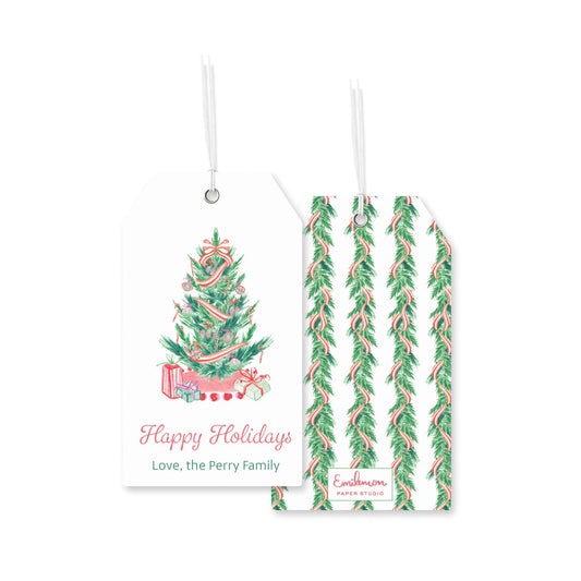 a white Christmas tree tag with a red ribbon and presents, and a second tag with a repeating pattern of green and red leaves.