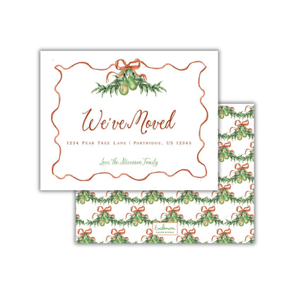 The image is a white envelope with a festive holiday-themed design, featuring a wreath of greenery and red ribbons. The text on the envelope reads "We've moved" and includes the address "1234 Pear Tree Lane / Portridge, US 12345".