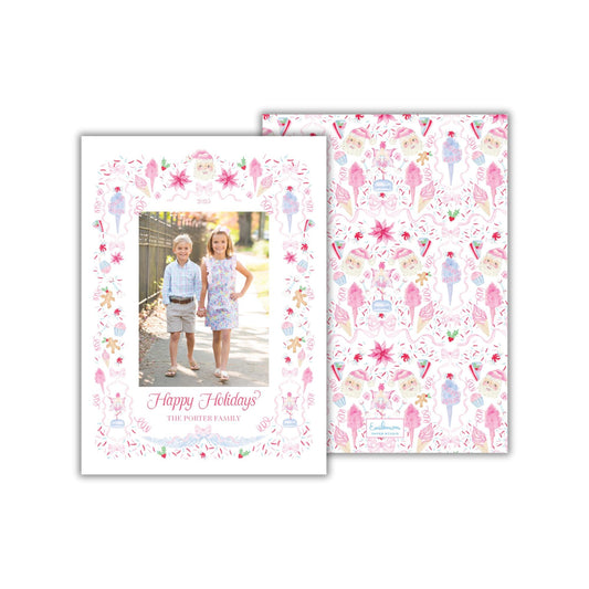 A holiday card featuring two children, likely siblings, standing together in front of a festive background with various holiday-themed illustrations.