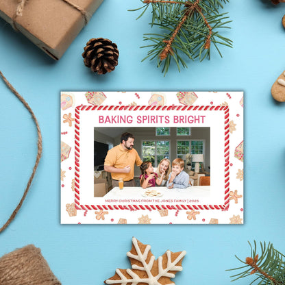 A framed photo of a family enjoying a holiday gathering, surrounded by festive decorations such as pine cones, gingerbread cookies, and a snowflake.