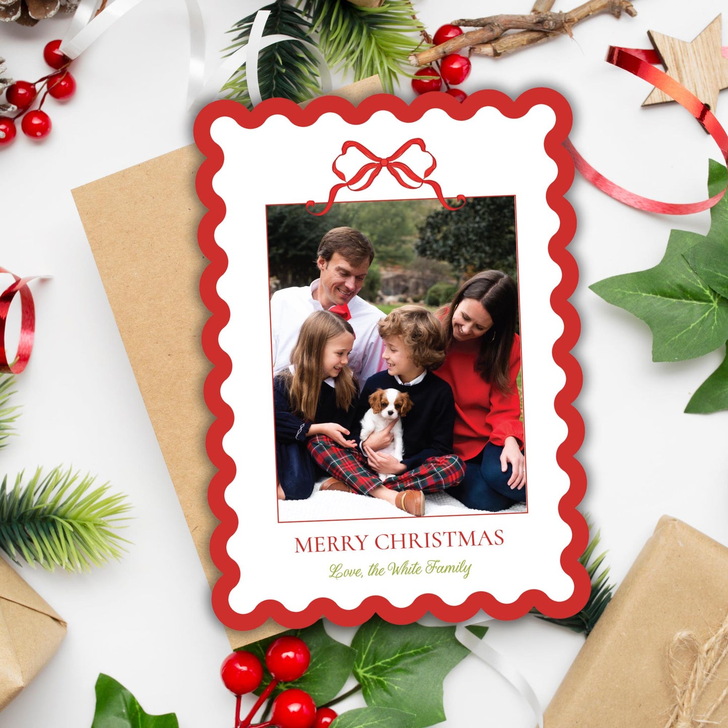 A family portrait of a man, woman, and child sitting together, with a dog in their lap, surrounded by holiday decorations such as pine branches, berries, and a star.