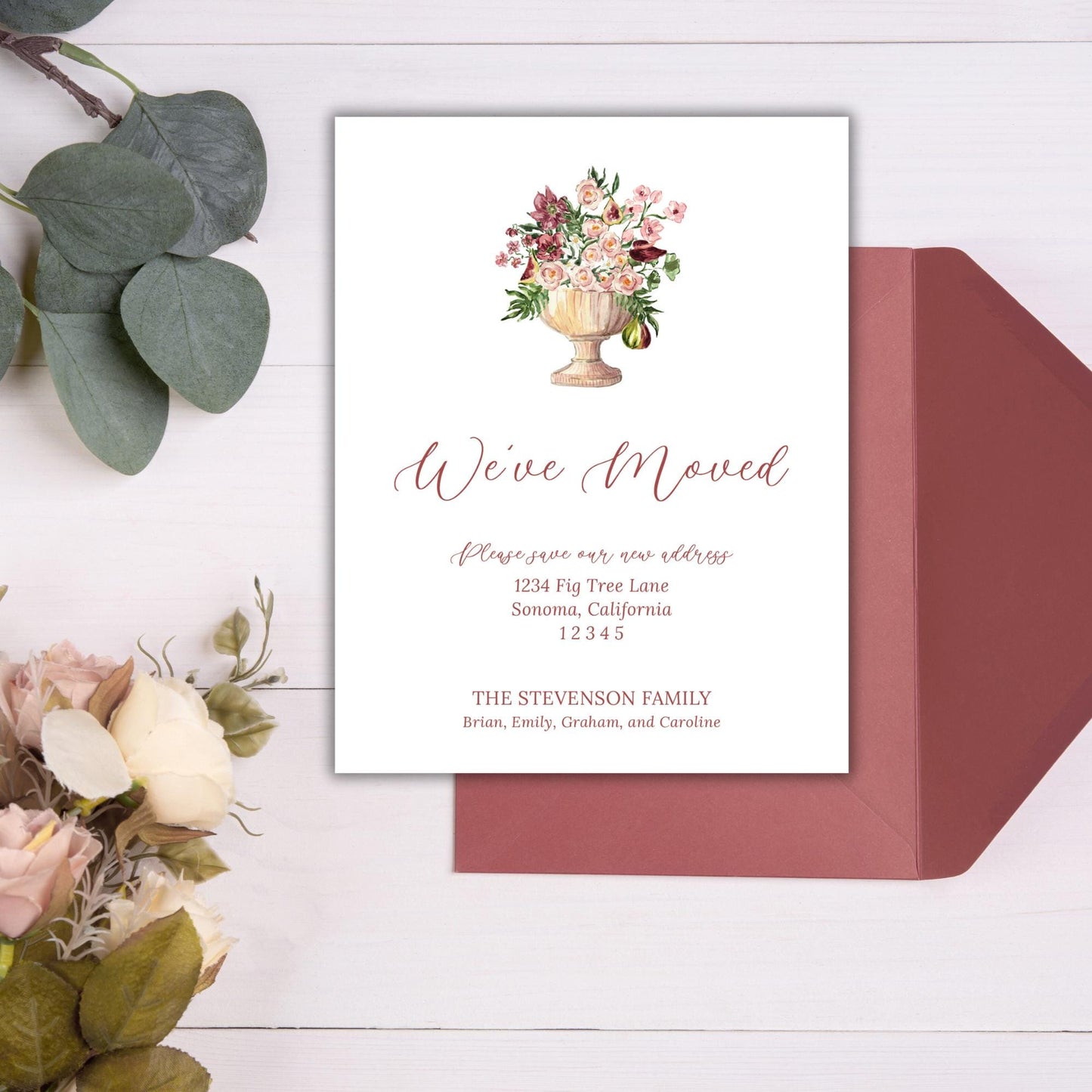 a wedding invitation card with a floral design and a red envelope placed on a white background.