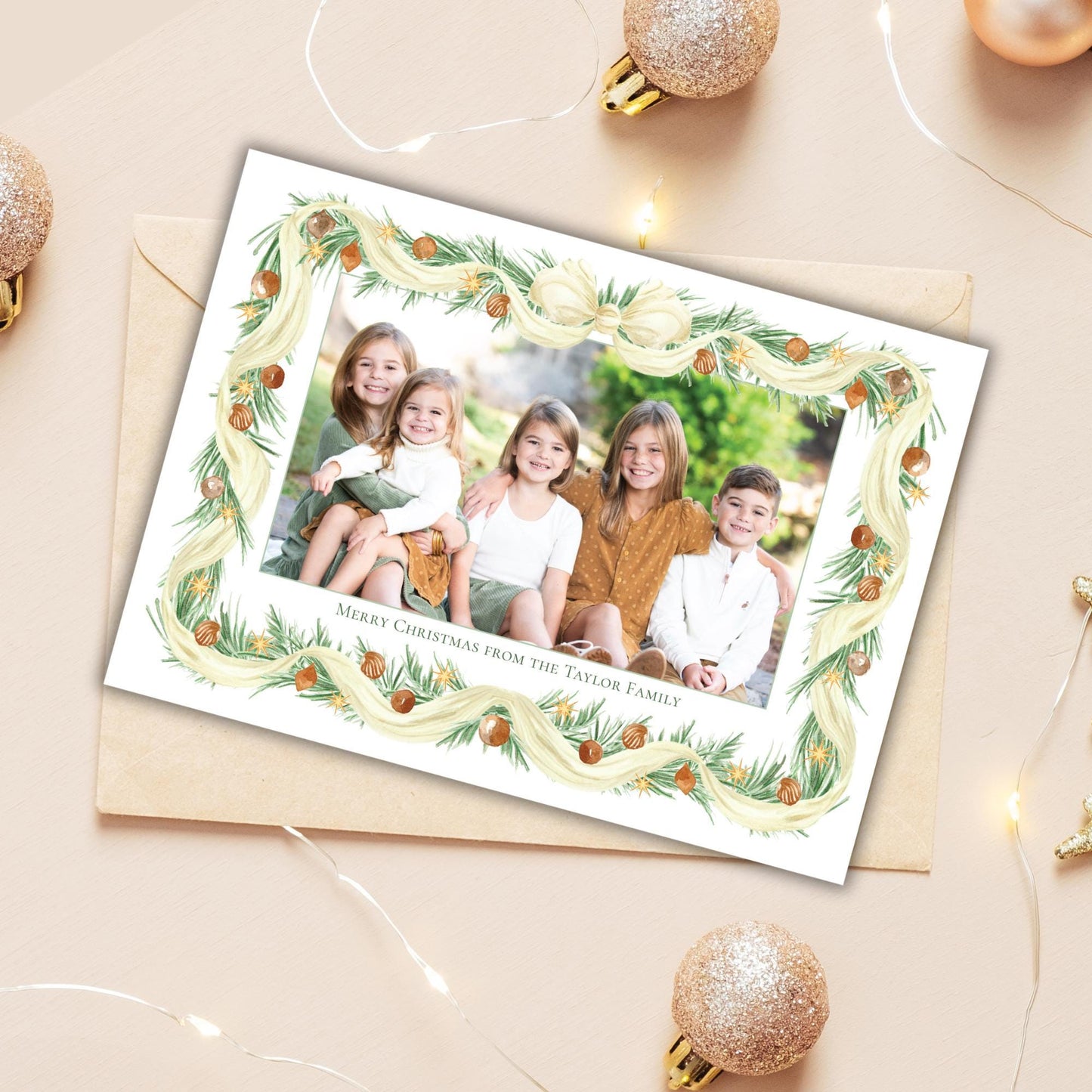 A family photo is displayed in a frame, surrounded by Christmas ornaments and lights on a light-colored surface.
