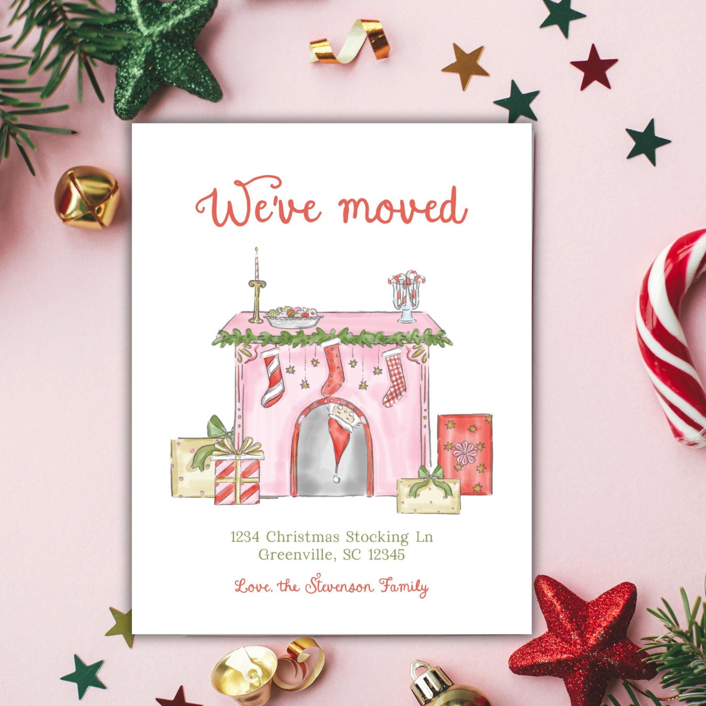 The image is a Christmas-themed greeting card with a pink background, featuring a house illustration surrounded by various holiday decorations such as stars, ornaments, and candy canes.