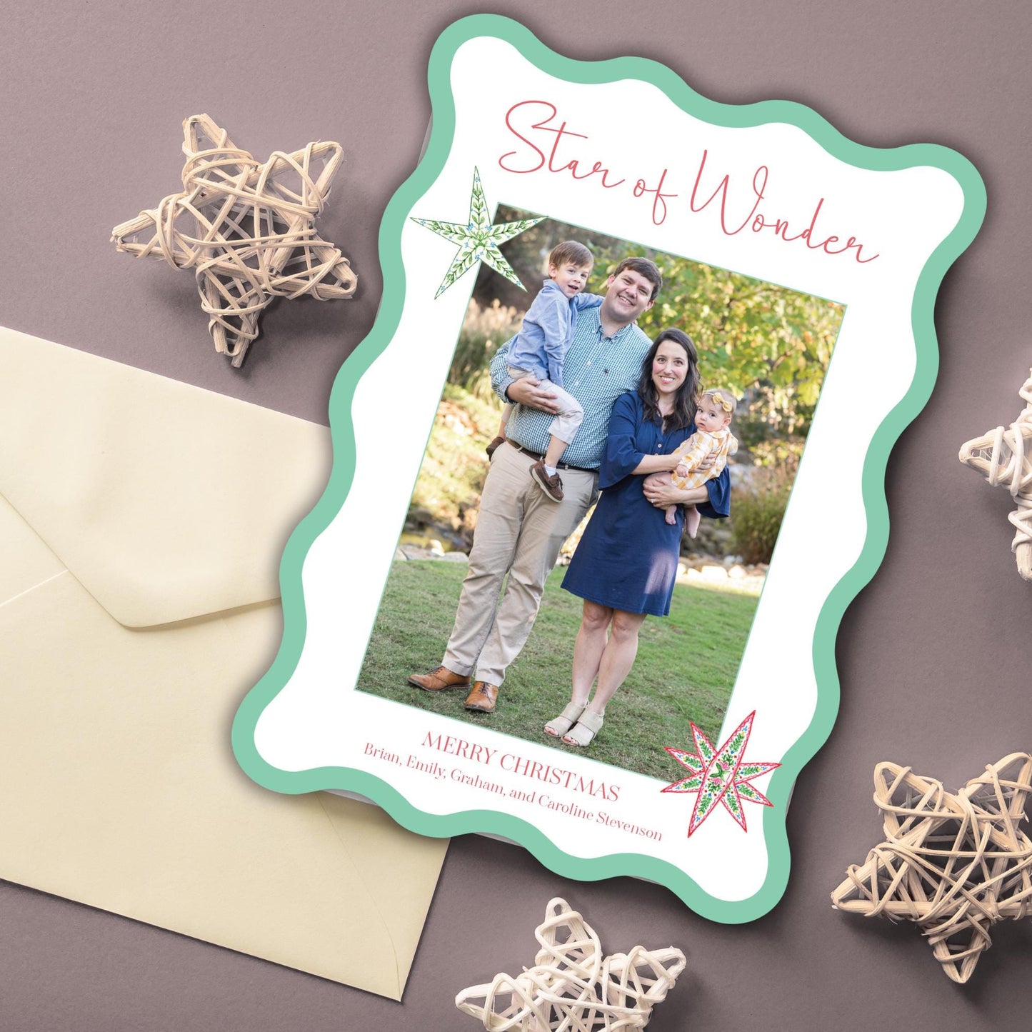 A family photo of a man, woman, and child is displayed on a green and white frame, accompanied by a greeting card and some decorative star-shaped objects.