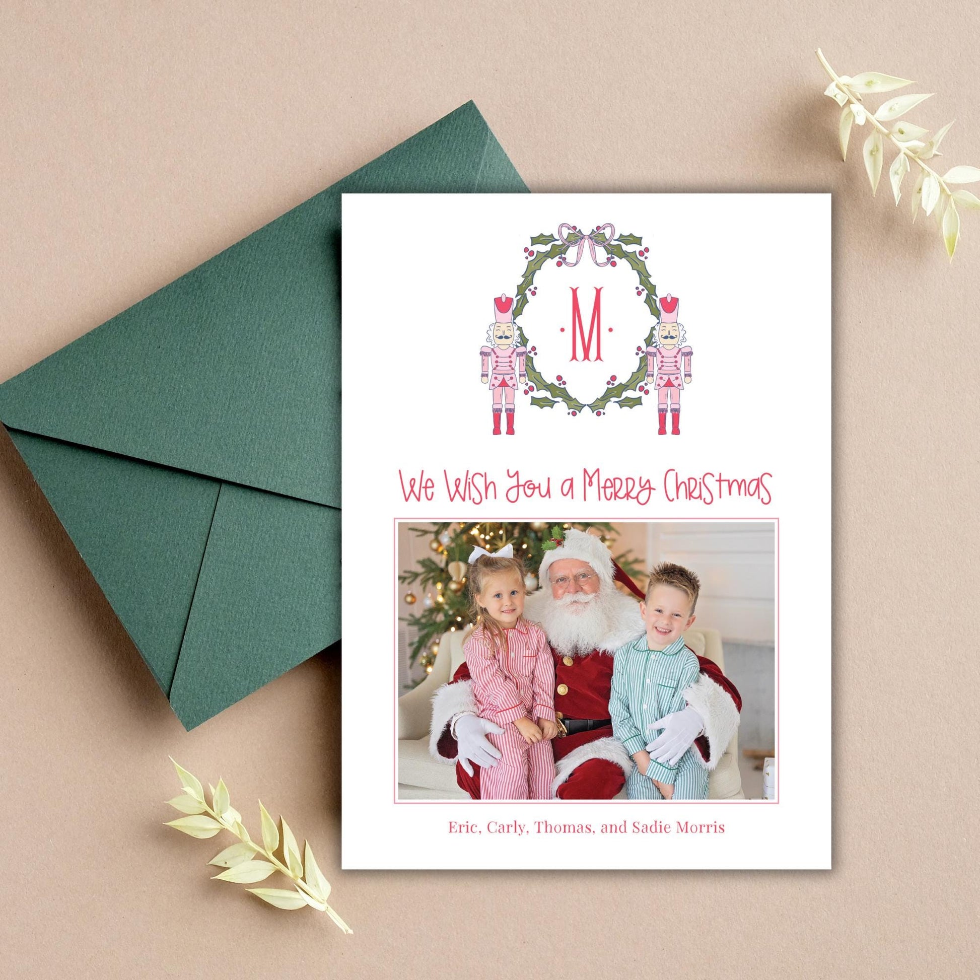 A Christmas card with a photo of a family, including a young girl, a boy, and an adult figure, along with a Santa Claus figure. The card has a green envelope and some leaves on the table.