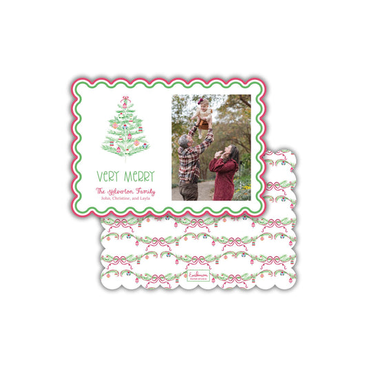 A Christmas card with a photo of a family, including a man, a woman, and a child, along with a Christmas tree design. The card has a scalloped edge and a floral pattern.