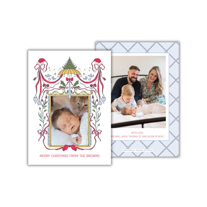 The image is a Christmas card featuring a family photo of a couple with their newborn baby. The card has a decorative border with a Christmas tree and other festive elements. The text on the card reads "Merry Christmas from the Browns" and "With love, Michael, Katie, Thomas (2) and Jacob (5) Mos".