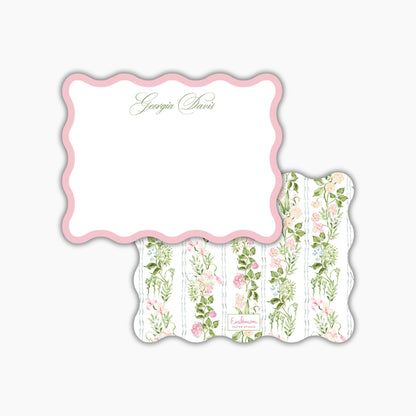 a pink scalloped frame with a floral pattern on the back.