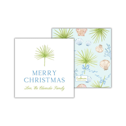 a greeting card with a tropical theme, featuring palm leaves and seashells. The card has a white background with a blue and green color scheme, and it displays the text "Merry Christmas Love, the Edwards Family" along with a decorative element resembling a palm tree.