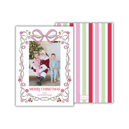 A Christmas card featuring a Santa Claus figure, with a family photo in the center. The card has a decorative border with pink and green stripes.