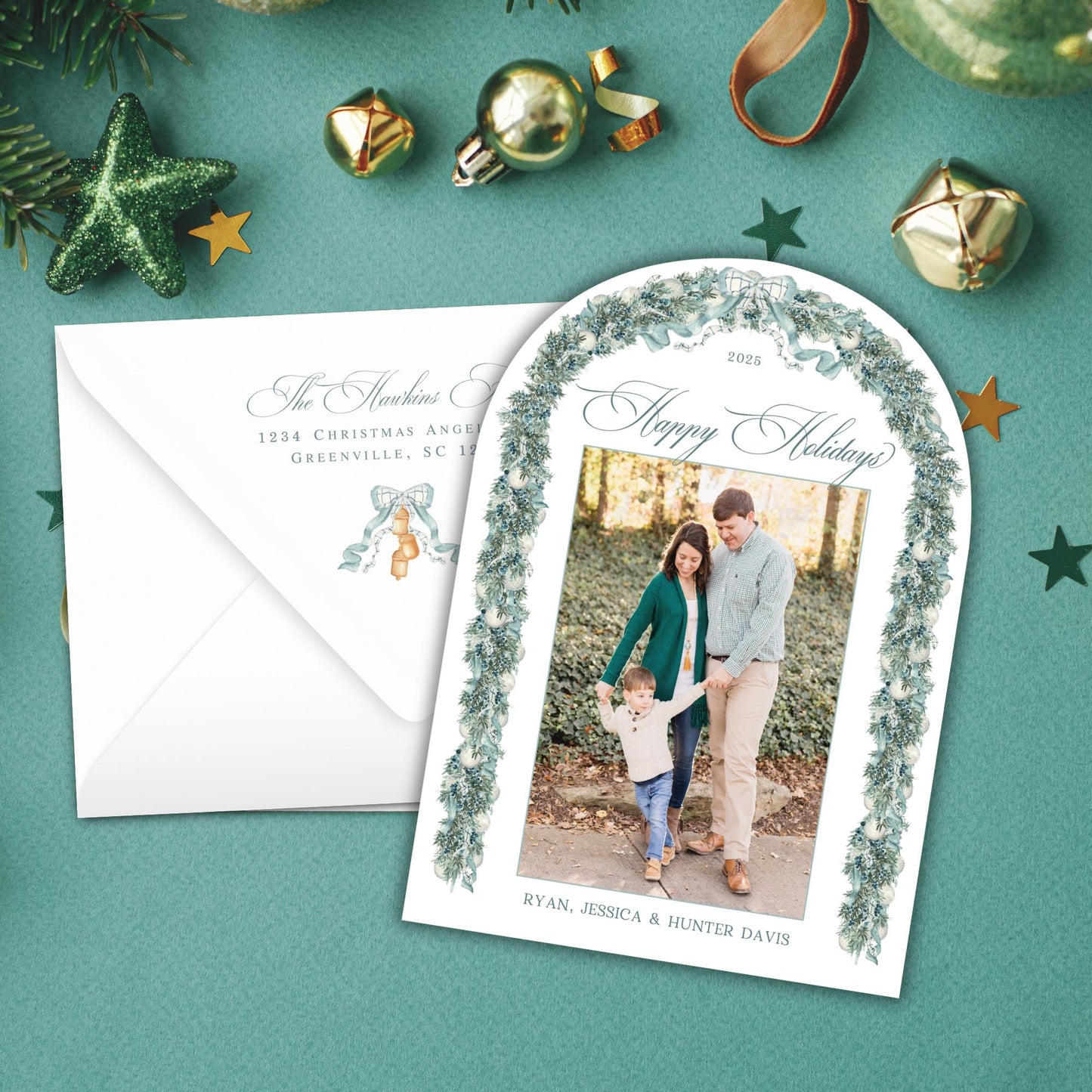 A holiday greeting card with a photo of a family, surrounded by Christmas decorations such as ornaments, tinsel, and a star on a teal background.